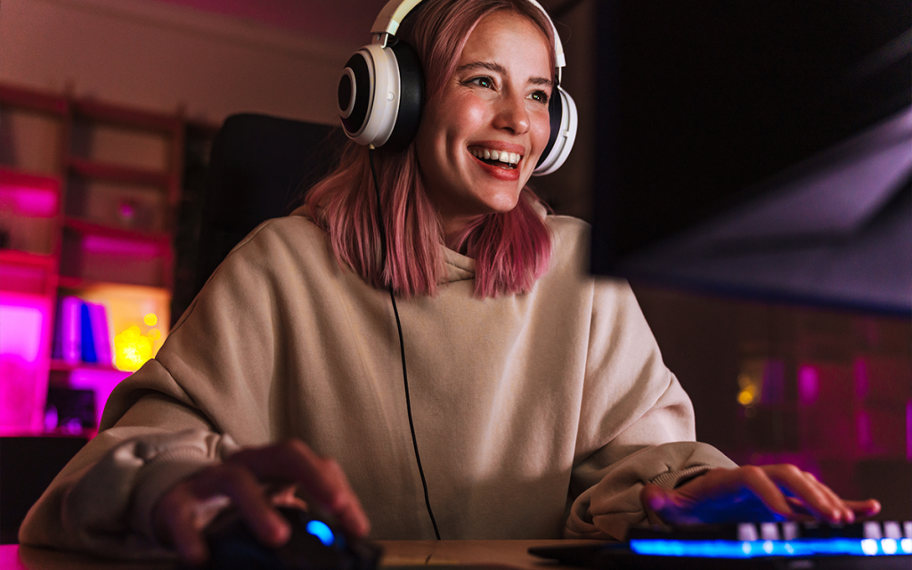 Mulher Gamer com headphone  jogando no computador com o mouse e o teclado