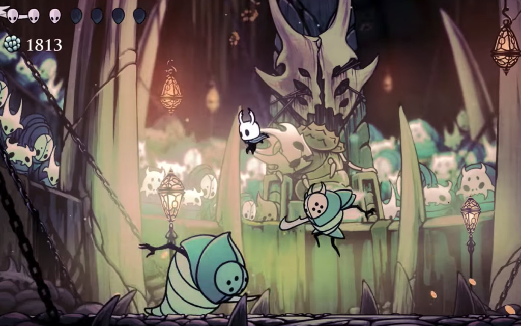 Imagem do jogo Hollow Knight com uma batalha do herói principal combatendo dois chefes de fase em uma arena com espectadores representando um jogo soulslike.