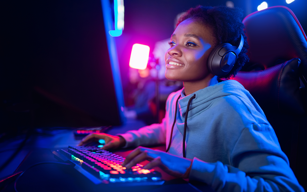 Mulher Gamer sentada em cadeira gamer usando headset na frente de computador.